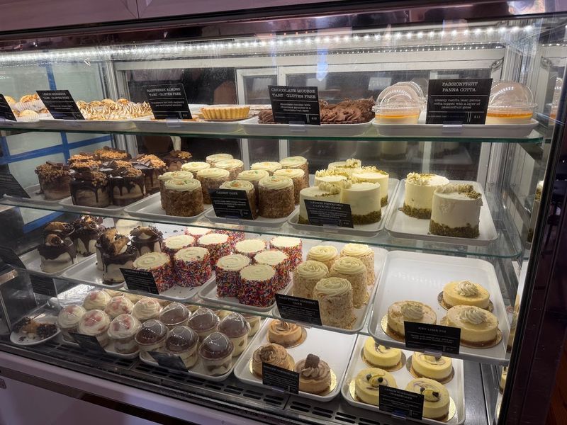 Cheesecake And Cakes Fill A Display Case That Stops People Mid-Step