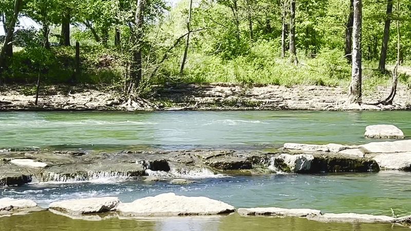 Sunlit Water Trails And Rocky Riverbanks